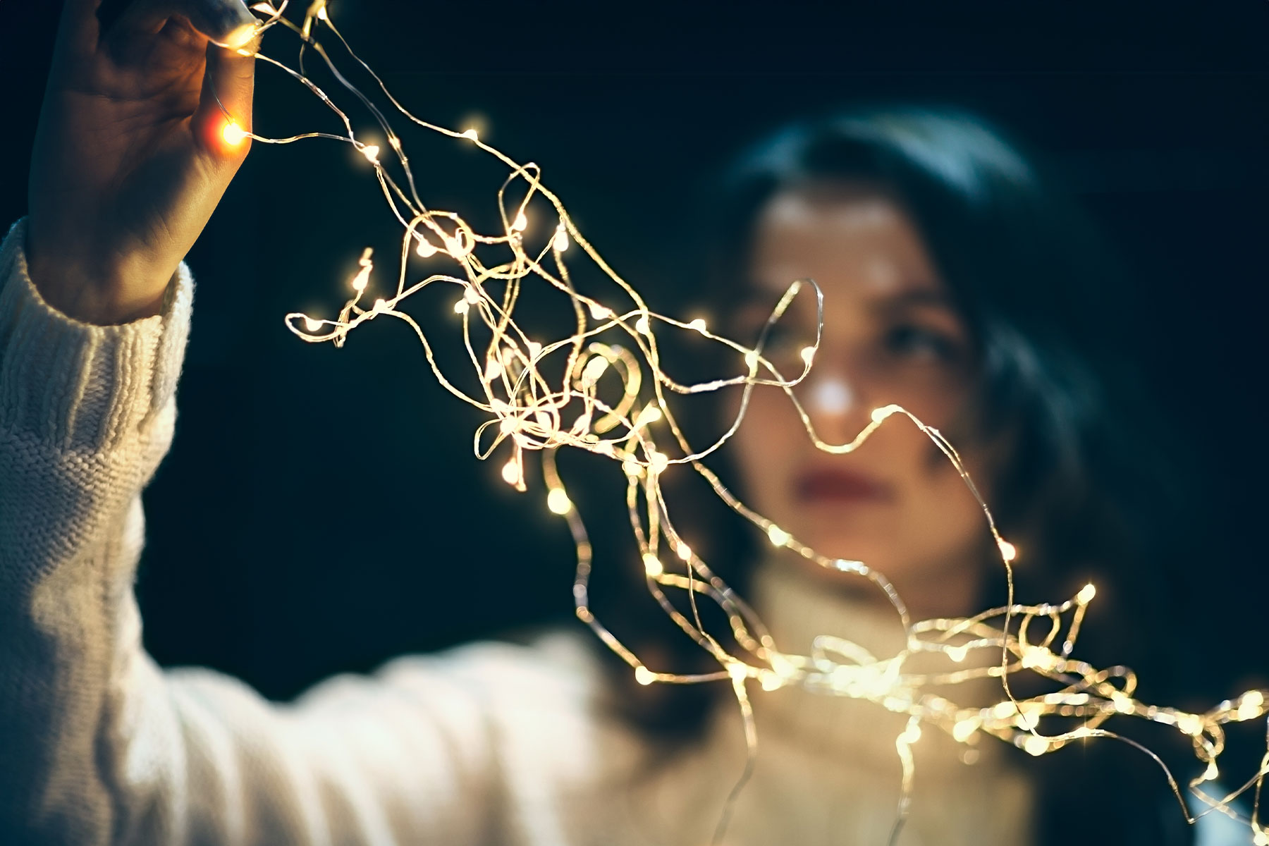 dark haired woman untangling clear holiday lights