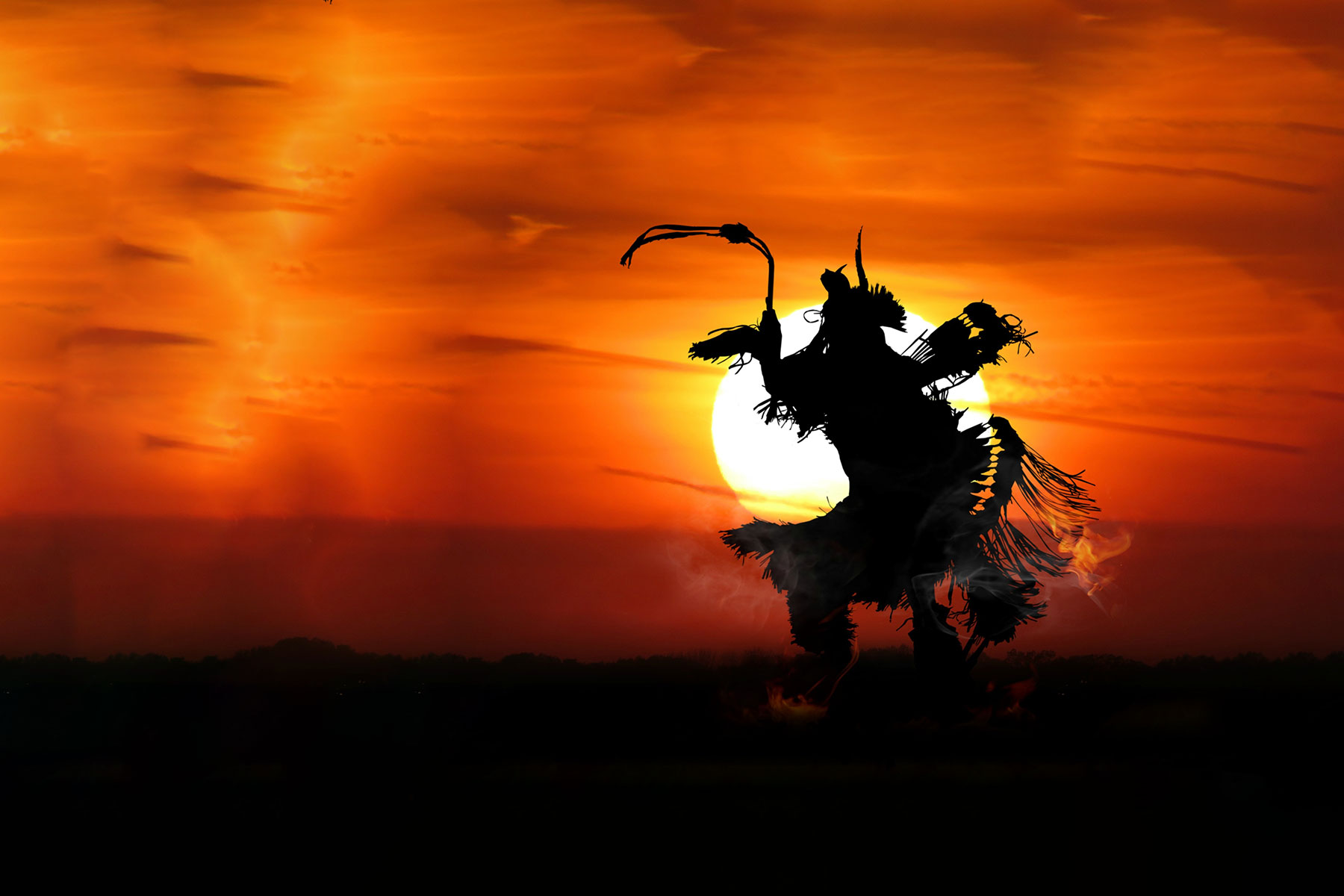 silhouette of native american male dancer in front of a sunset