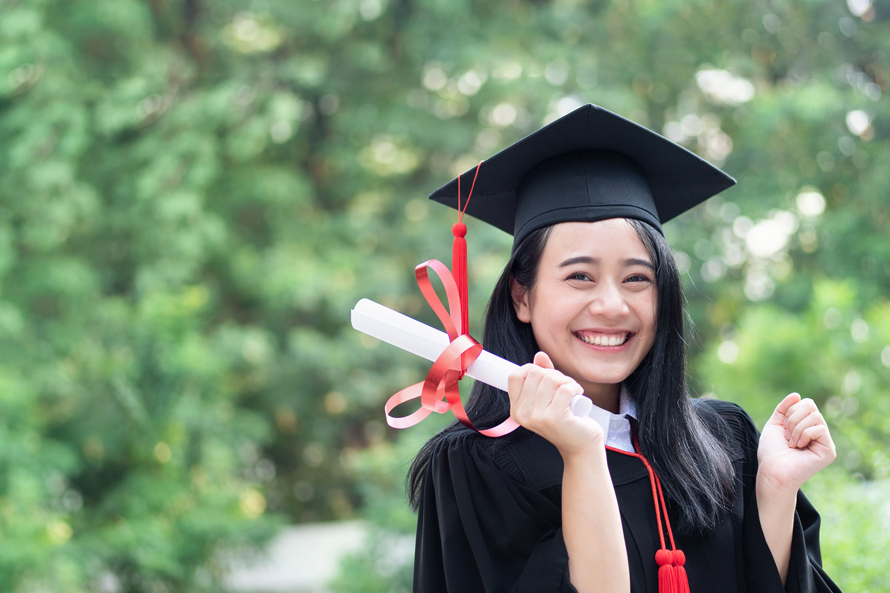 happy female asian graduate holding diploma