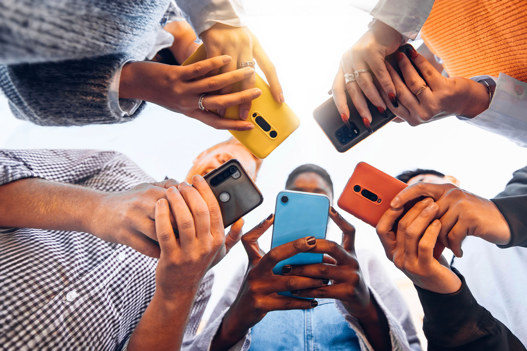 view from below a group of young friends standing in a circle all holding their phones