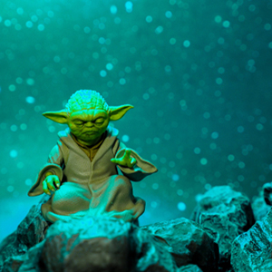 yoda sitting in a meditative pose on rocks under a green light