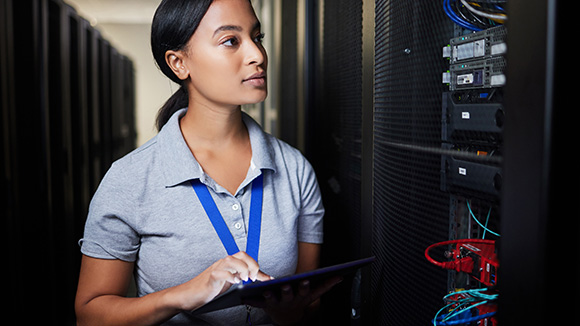 Woman holding tablet and thinking in server room, inspecting servers