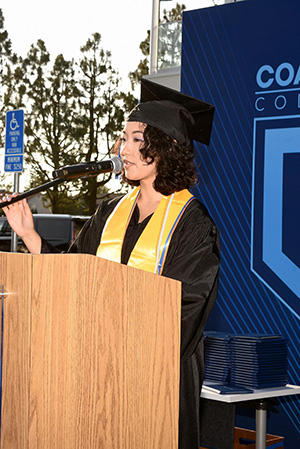 Lexi standing at a podium speaking at the Coastline College commencement ceremony