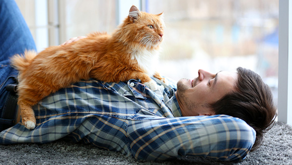 Young man with ginger fluffy cat lying on a carpet