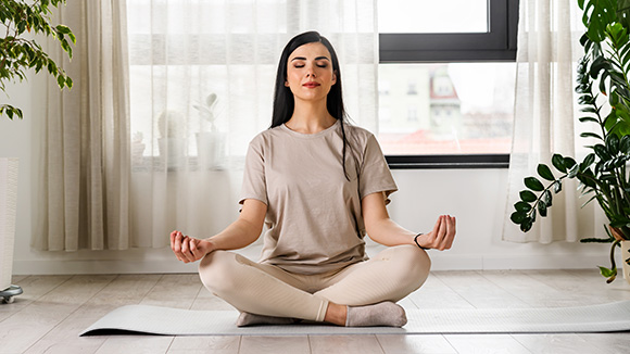 young woman doing meditative yoga in an airy room surrounded by plants