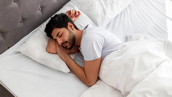 young man sleeping peacefully in a large white bed