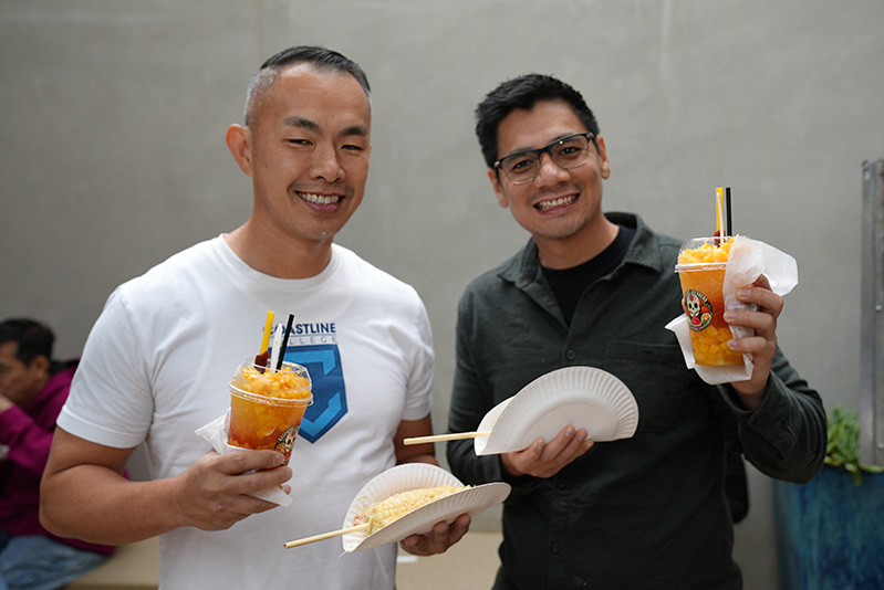 students holding up corn on a stick and icy drink